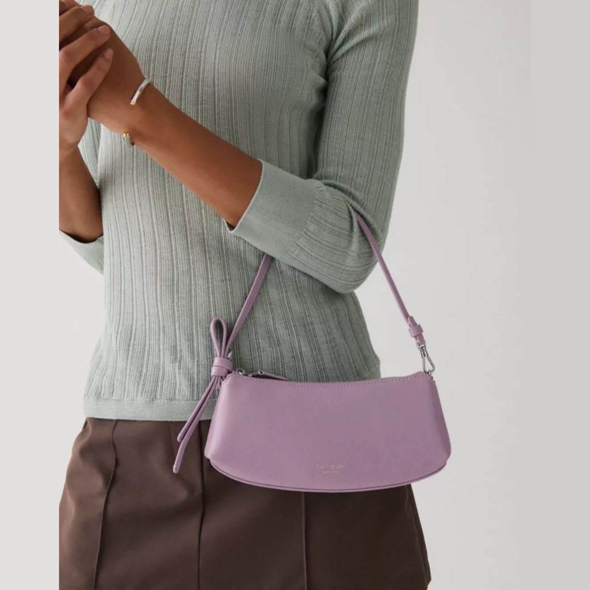 Bolso mini Loop cuero brillante violeta con correa anudada y cierre superior, estilo pochette.